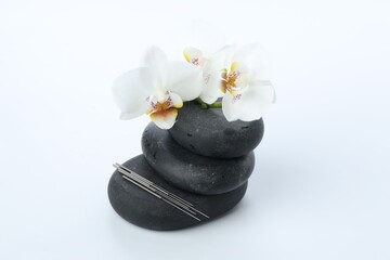 Acupuncture needles, orchid flowers and spa stones on white background