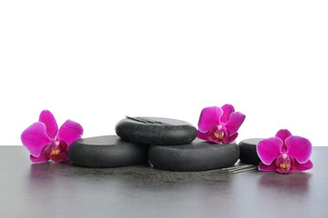 Fototapeta premium Acupuncture needles, orchid flowers and spa stones on grey textured table against white background
