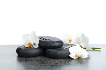 Acupuncture needles, orchid flowers and spa stones on grey textured table against white background