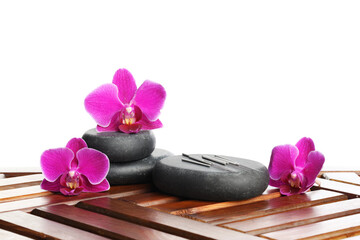 Acupuncture needles, orchid flowers and spa stones on wooden table against white background