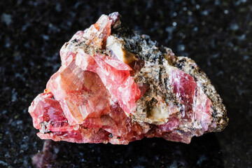 sample of raw rhodonite mineral on black