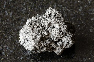 sample of raw pumice mineral on black granite