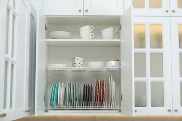 Clean dishware and cups on shelves in cabinet indoors