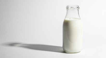 A classic glass bottle of fresh white milk with a long shadow, isolated on a clean white background.