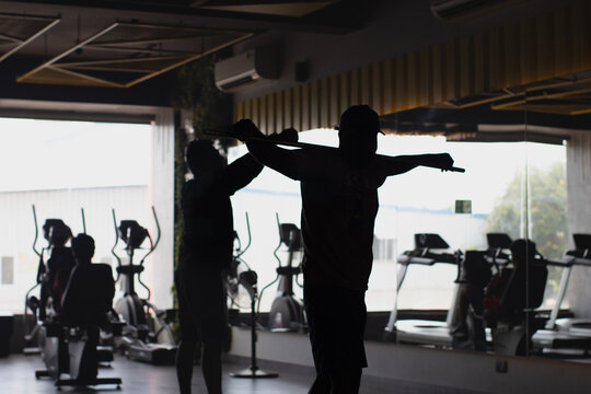 Silhouette of men workout in the fitness center during day time to maintain the physic