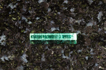 sample of raw emerald crystal on black granite