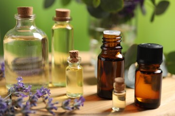 Bottles of essential oils and different plants on table outdoors, closeup