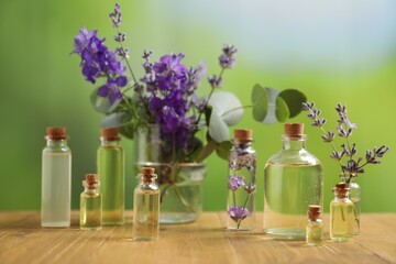 Bottles of essential oils and different plants on wooden table outdoors, closeup
