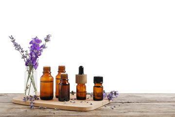 Bottles of essential oils and different plants on wooden table against white background