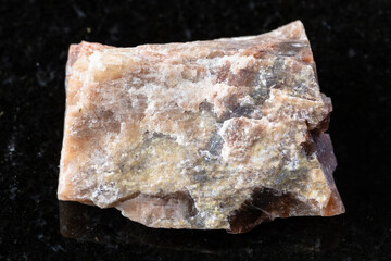sample of raw nepheline rock on black granite