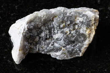sample of rough melilite rock on black granite