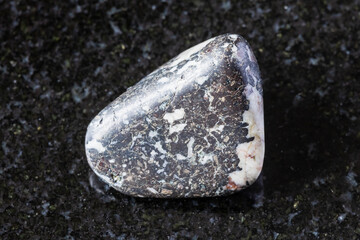 sample of tumbled trachybasalt rock on black