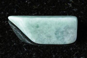 sample of tumbled jadeite mineral on black granite