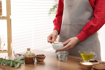 Making natural scrub. Woman adding sugar into jar at wooden table, closeup
