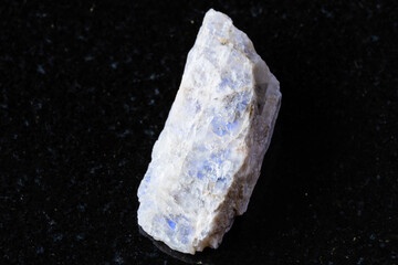 sample of raw belomorite mineral on black granite