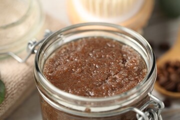 Natural body scrub in glass jar on table, closeup