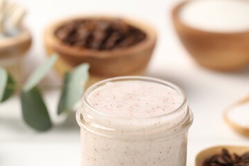 Natural body scrub in glass jar on blurred background, closeup