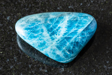 sample of tumbled apatite rock on black granite