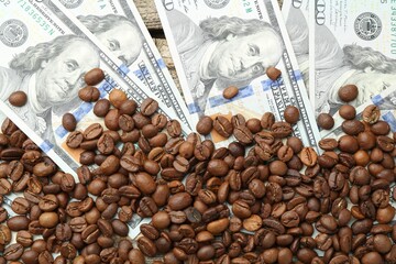 Dollar banknotes and coffee beans on table, top view