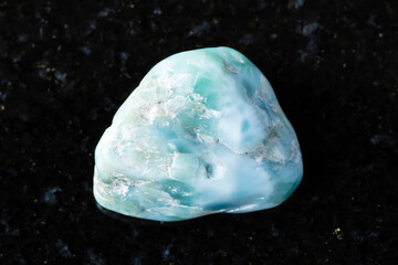 sample of raw larimar mineral on black granite