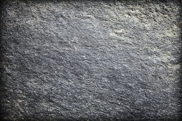 Close-up view of a dark gray stone surface.  Textured, rough, and uneven.  A slightly aged or weathered look