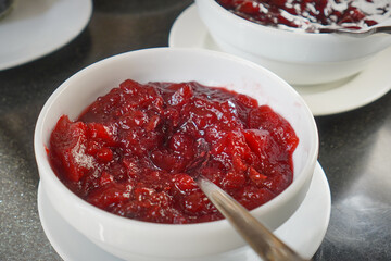 Bright red berry sauce served in a white bowl as a dessert topping or spread