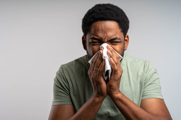 Man blowing nose isolated on white background with allergy or flu symptoms, sick adult male health...