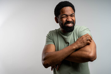 Young black man scratching hands from allergy or insect bite, feeling strong discomfort on isolated...
