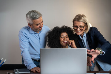 Three busy happy middle aged professional business man and two women executive leaders team using laptop working on computer at work desk having conversation on financial project at meeting in office.