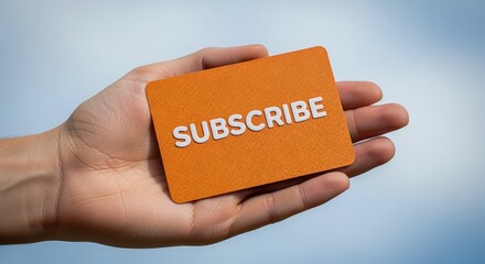 Hand Holding Orange Card with the Word Subscribe on a Blurred Light Blue Background