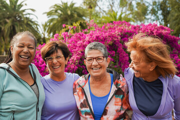 Obraz premium Happy multiracial senior women having fun together outdoor - Elderly generation people hugging each other at city park
