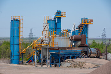Asphalt mixing plant on construction site under cloudy sky in rural landscape. concept of heavy...