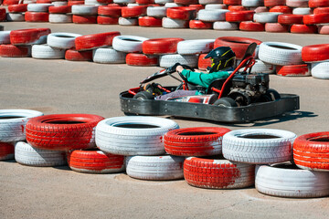 A man is driving a go kart on a track with red and white tires