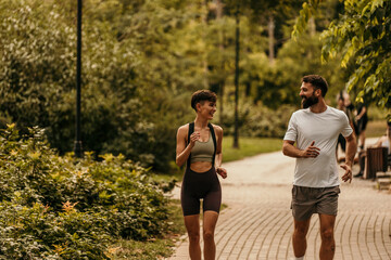 Happy couple jogging together in lush green park