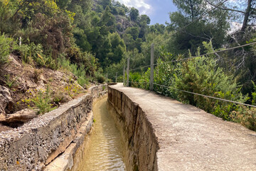Scenic view of surrounding mountains and picturesque village from a hiking trail along an old irrigation ditch in Frigiliana, Spain.