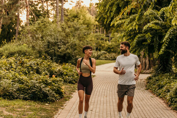Obraz premium Couple running and talking in a green park during summertime