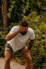 Exhausted male runner suffering headache after intense workout in park