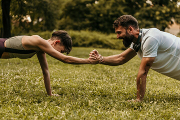 Couple doing plank exercise and holding hands in park