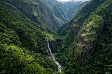 Majestic waterfall cascades down rocky cliffs in lush green valley surrounded by mountains and misty skies