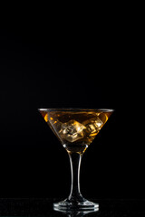 Classic cocktail glass filled with whiskey and ice cubes, photographed in close-up, against a dark black background for a premium beverage concept