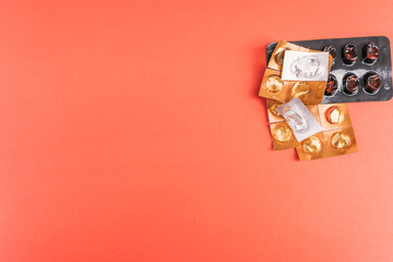 Empty pills and blister packs in various shapes on a vibrant red surface, top view