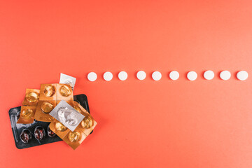 Empty pills and blister packs in various shapes on a vibrant red surface, top view
