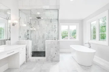 Fotobehang Hotel chique A luxurious bathroom with a freestanding tub, white vanity, and a glass walk-in shower with marble tiles and bench seat.  © Joseph Hendrickson