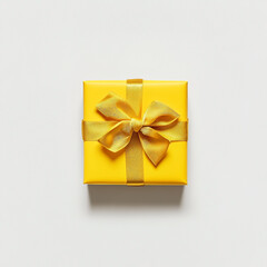 Bright yellow gift box with golden ribbon and bow on white background present