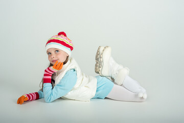 Cute smiling girl in winter clothes with vest and Santa Claus hat sits on the floor, copy space. Christmas and New Year sale concept. Mockup for advertising