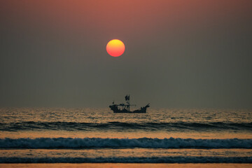sunset over the sea, view from the beach,  a boat sailing under the sun