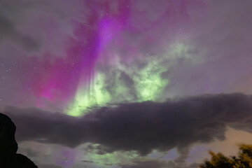 The stunning Northern Lights over Lofoten Islands, Norway, with vivid colors lighting up the night sky above mountains.