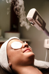 beautiful woman in spa salon getting face treatment with hot steam