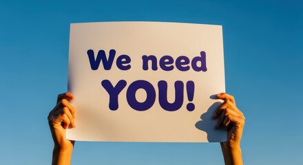 A Sign Held Up Against a Blue Sky Reading 'We Need You', Recruitment Advertising
