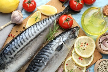 Fresh raw mackerels and spices on light blue wooden table, flat lay. Seafood delicacies